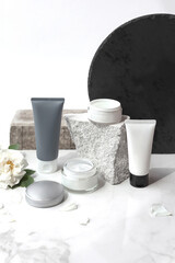 Mock up. Jar and tubes of cream or body lotion, white and gray, on a pieces of stone on a white background with flower, rose. Natural cosmetics. Treatment spa beauty skincare. Healthcare, medicine