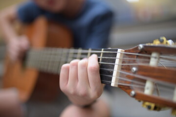 Fototapeta premium A young kid playing guitar outdoors