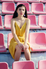 Young woman is sitting on a stadium chair alone.