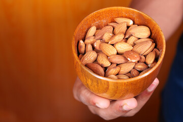 close up man hand holding a bowl full of almond 