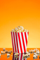 Red and white Popcorn box filled with popcorn on orange background