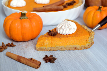 pumpkin pie with cinnamon and cream in a cut. Autumn table setting for Thanksgiving and Halloween....