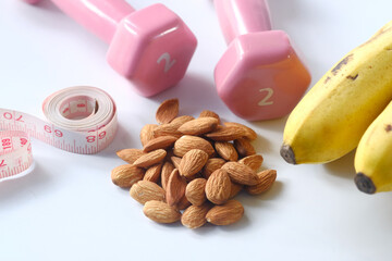Diet plan with almond nut, dumbbells, banana on table .