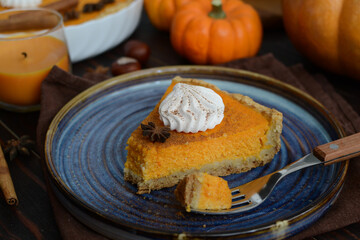 pumpkin pie with cinnamon and cream in a cut. Autumn table setting for Thanksgiving and Halloween. pumpkins, cinnamon sticks, plates, wooden background