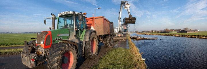 Dredging of inland canals by pushboat and crane; the dredging spoil is deposited in a tipper trailer