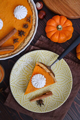 pumpkin pie with cinnamon and cream in a cut. Autumn table setting for Thanksgiving and Halloween. pumpkins, cinnamon sticks, plates, wooden background