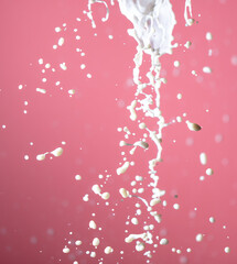 Splashes of white milk on a pink background.