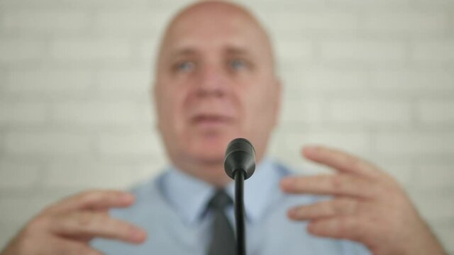 Blurred Image of a Politician in a Press Conference Speaking at the Microphone and Gesturing