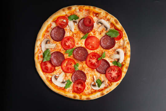 pizza with tomatoes, pepperoni and herbs