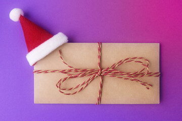Envelope with small red Santa hat on violet background