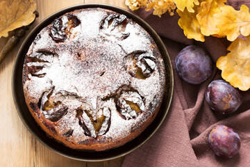 Plum pie with nuts and chocolate on a wooden background. Rustic style.