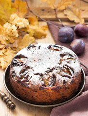 Plum pie with nuts and chocolate on a wooden background. Rustic style.