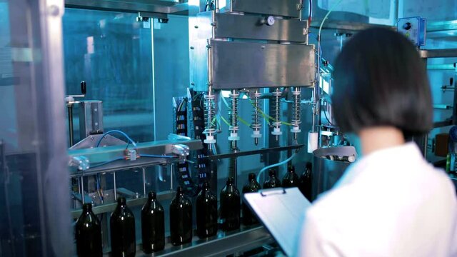 Giovane dottoressa con camice bianco sta guardando la qualit&agrave; della produzione nella fabbrica 