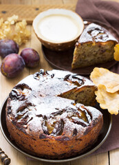 Plum pie with nuts and chocolate on a wooden background. Rustic style.