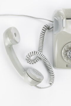 Studio photo of gray vintage rotary telephone in bright setting.