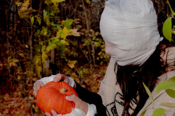 Portrait of a woman in a mummy halloween costume with a pumpkin. She is ready for a Halloween party...