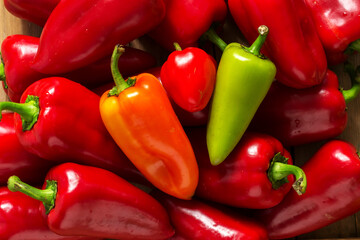 Sweet peppers of various colors on a wooden surface.