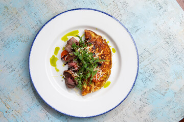 omelet with beef slices and arugula on a plate