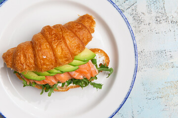 croissant with salmon and avacado in a plate