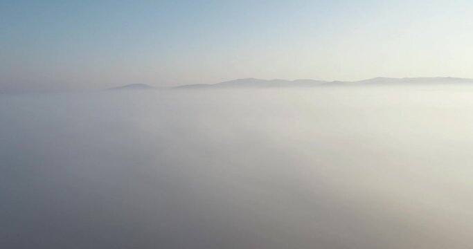 Above the fog in mountains landscape / misty view mountain under the clouds. Aerial drone wide view at summer sunset
