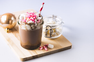 Glass Jar of Tasty Hot Cocoa or Chocolate Decorated with Marshmallow and Crumbled Candy Cane Christmas Beverage Blue Background Horizontal