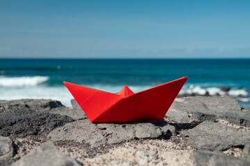 Red paper boat in front of the ocean outdoors