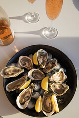 Fototapeta premium Oysters with lemon and two glasses of rose sparkling wine.
