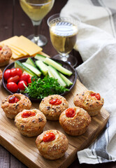 Muffins with cheese, cottage cheese and tomatoes, vegetables and cheese served with wine.