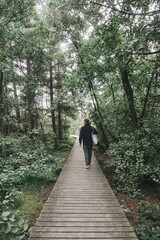 Fototapeta na wymiar Junger Mann läuft barfuß über einen Holzsteg im Wald auf Amrum