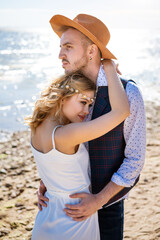 Happy young beautiful couple in an embrace on the shore of the sea