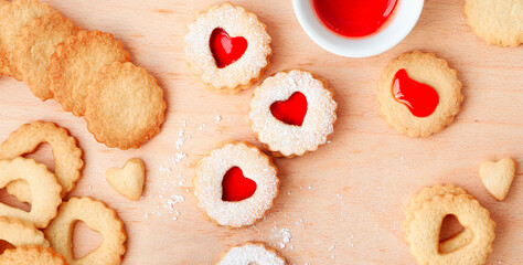 Top panoramic view of Christmas Linzer cookies filled with red jam on wooden board. Heat shapes.