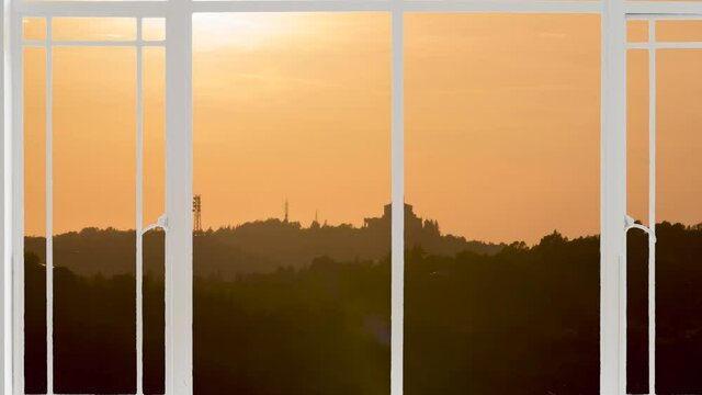 Basilica or church of Saint Luca in Bologna landscape as seen from a white window while birds are flying at the sunset. It is seen the hills or colli in close up and the cathedral in background