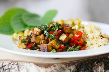 Gebratener Tofu mit Paprika und Sesamblättern, Bratkartoffeln und Sauerkraut, veganes Mittagessen für einen gesunde Ernährung