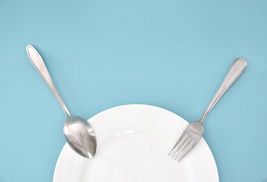 A tablespoon and fork, laid out at one end on a white plate.