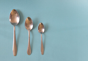 Three spoons of different sizes laid out in a row on a light blue background.