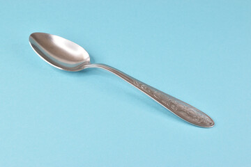 Stainless steel table spoon isolated on light blue background.