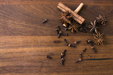 Cinnamon, star anise, cloves on dark brown wooden background, christmas concept with copy space