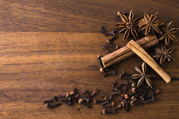 Cinnamon, star anise, cloves frame on dark brown wooden background, christmas concept with copy space