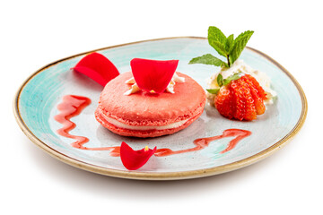 Pink dessert Macarons with cream and strawberries on a blue plate