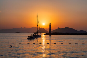 Lighthouse at sunset in Mediterranean islands and marina with yachts in Bodrum, Turkey.