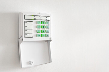 Electronic control panel of the apartment and office security alarm system with electronic keypad on a white wall