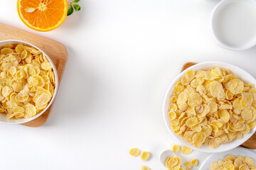 Top view of corn flakes bowl with milk on white background.