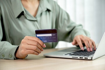 Businesswoman hand holding and use credit card to online shopping from home with laptop, payment e-commerce, internet banking, spending money for next holidays