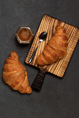 French fresh baked croissants with jam on dark stone background. Breakfast bakery concept