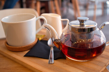 Glass pot and cup of delicious black tea for autumn day