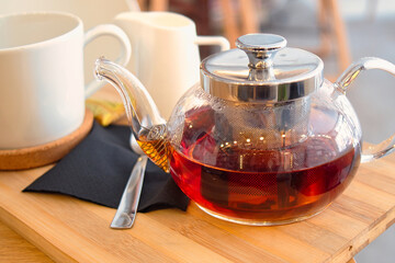 Glass pot and cup of delicious black tea for autumn day