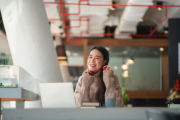 Portrait of female teenager in sweater with headphone relaxing in co working space.
