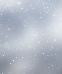 White snowflakes on a gray blurred inhomogeneous background, winter abstract background