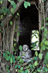 The Buddha statue at the window of the old church between bodhi root tree at Wat Bang Kung temple in Samut Songkhram province, Thailand 