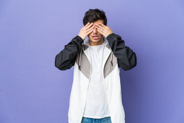 Young cool man afraid covering eyes with hands.